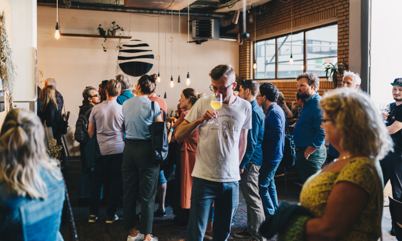 Mensen binnen in het Nevel proeflokaal in het Honigcomplex